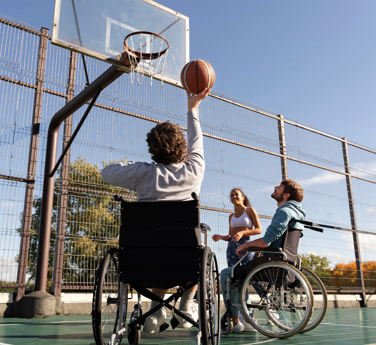 Rollstuhlfahrer wirft einen Basketball auf einen Outdoor-Korb