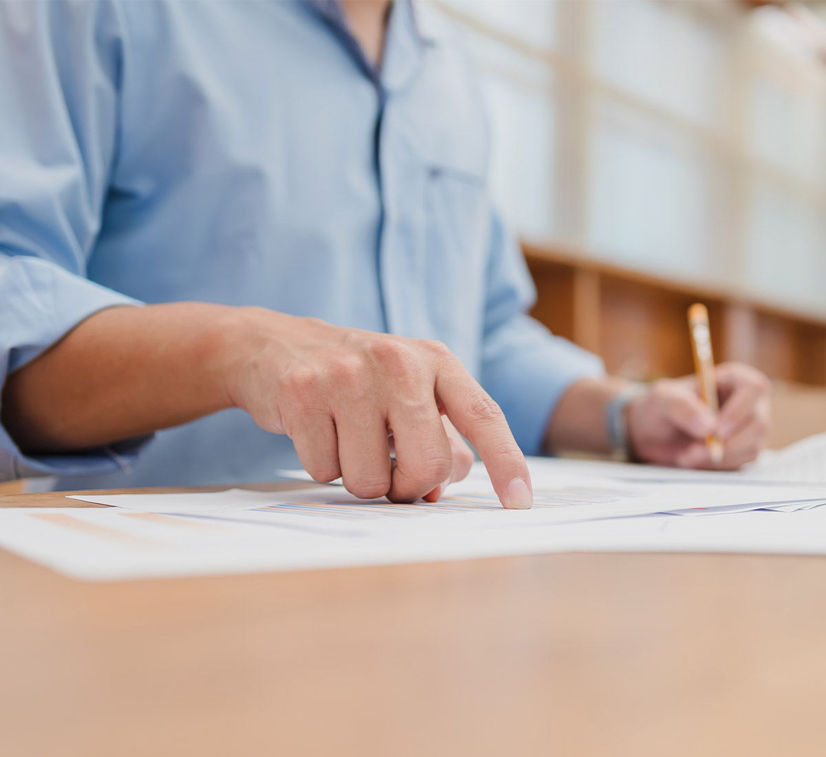 Männliche Person schreibt und arbeitet am Schreibtisch
